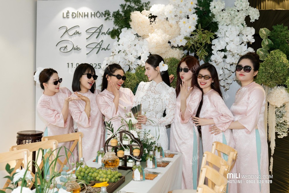 Cô dâu và bạn bè chụp ảnh trước phông lễ xanh trắng
