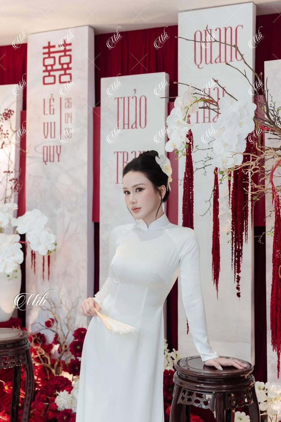 Cô dâu bên phông lễ đỏ trắng và hoa lan trắng