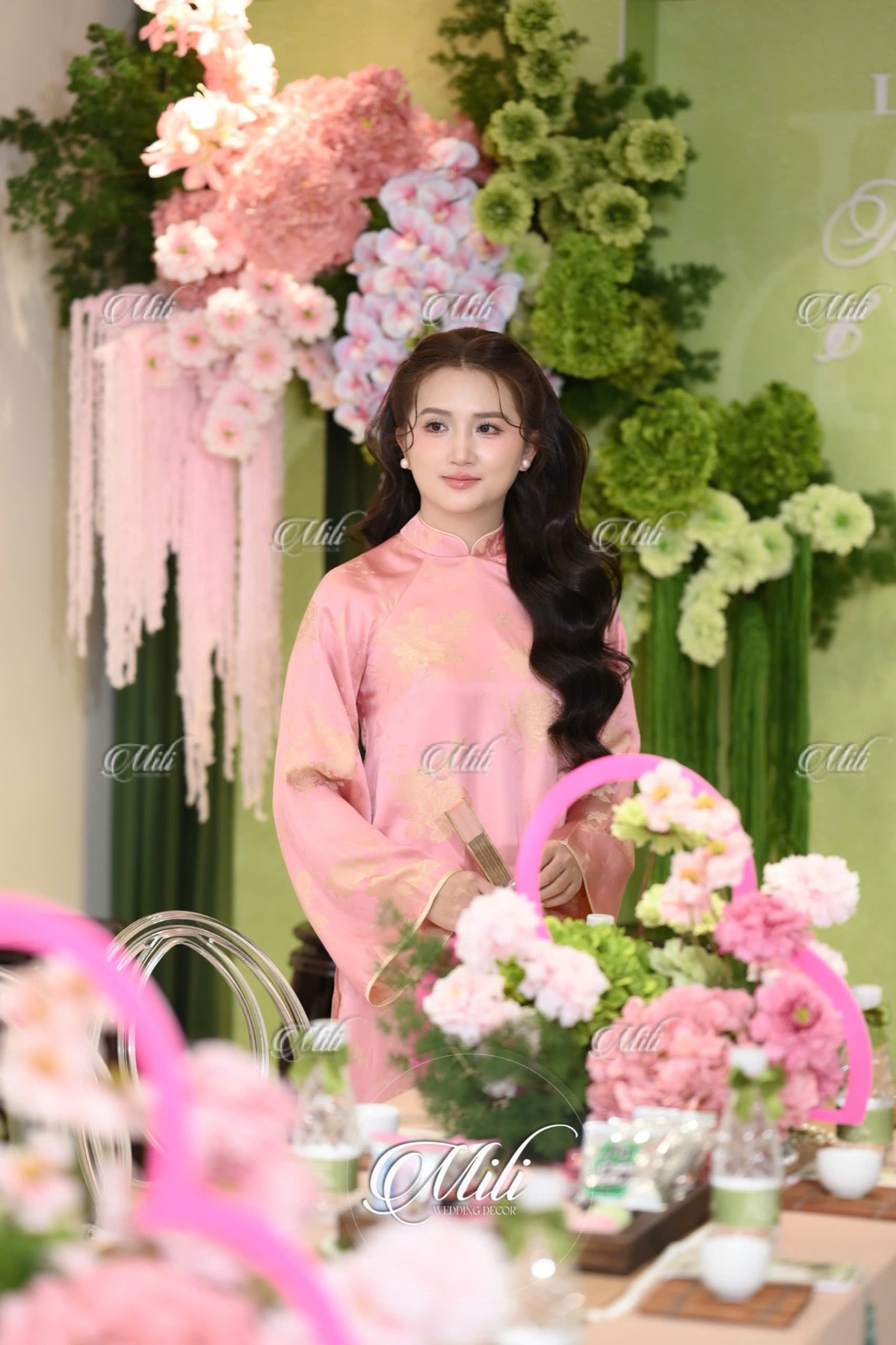 Chân dung cô dâu áo dài hồng trong phòng lễ xanh lá hồng phấn